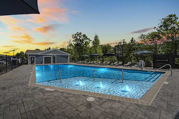 A large outdoor swimming pool with a sunset sky in the background.