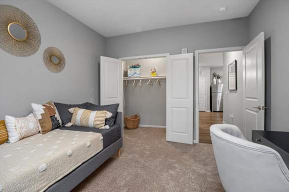 A bedroom with a bed, chair, and wardrobe.