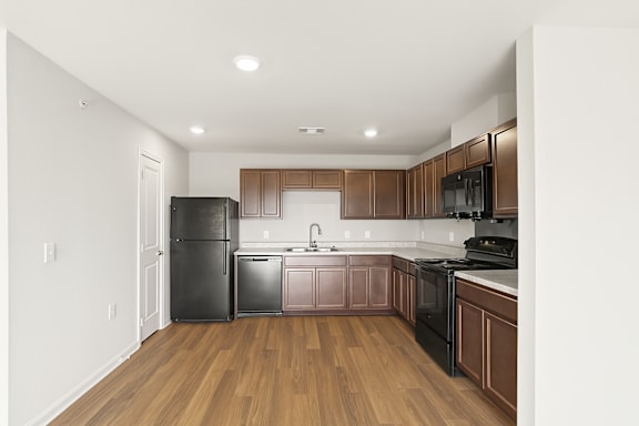 A kitchen with wooden floors and brown cabinets.
