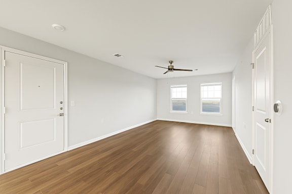 A room with a ceiling fan and wooden floors.