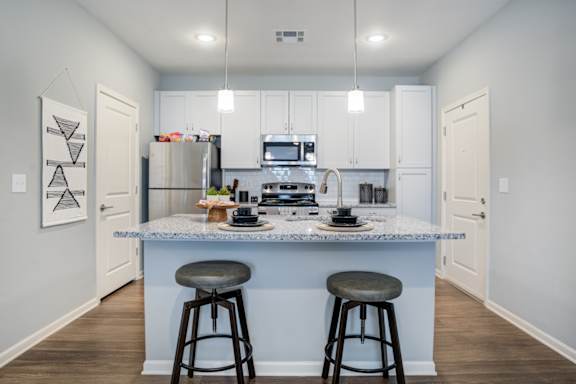 A kitchen with a bar stool in front of the island.