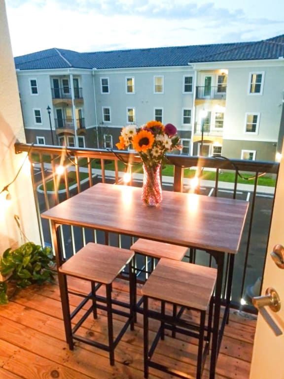 Balcony with table, chairs and lights at Flats At Sundown