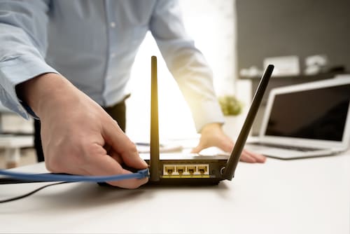 Person plugging a cable into a modem