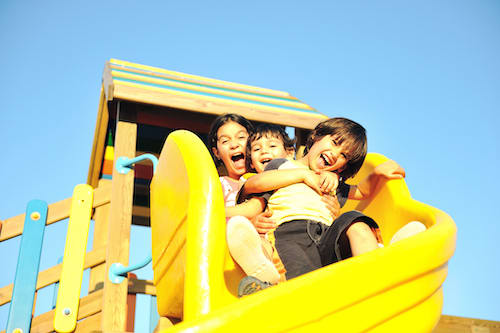 Children sliding down a slide together