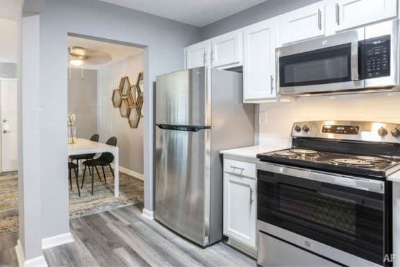 a kitchen with white cabinets and stainless steel appliances at at Station JTown, Kentucky, 40299