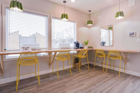 a long table with yellow chairs and a mirror on the wall at Stonewater Apartments, Louisville, KY