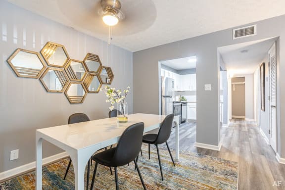 a dining room with a table and chairs and a kitchen in the background at at Station JTown, Kentucky, 40299