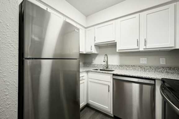 a kitchen with white cabinets and a stainless steel refrigerator at Southridge, Kansas City, KS, 66103