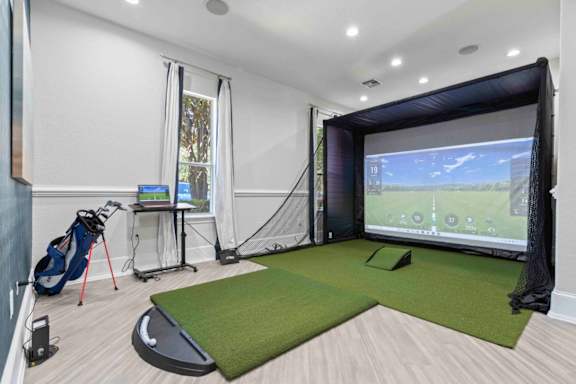 A room with a golf simulator and a golf bag.at Elan Apartments, Fort Walton Beach, FL