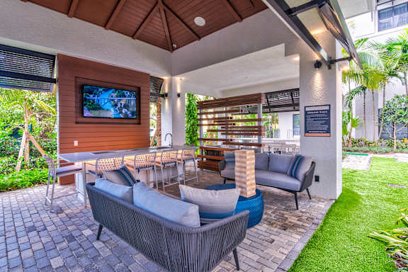 A patio with a couch, chairs, and a television at Mayla Pompano, Pompano Beach, Florida