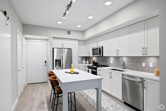 A modern kitchen with a white island and stainless steel appliances.