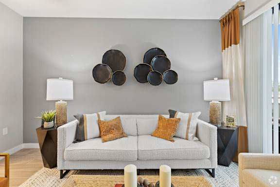 A living room with a white couch and a large abstract art piece above it.