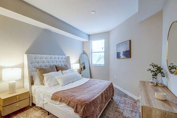 A bedroom with a large bed and a lamp on the nightstand.