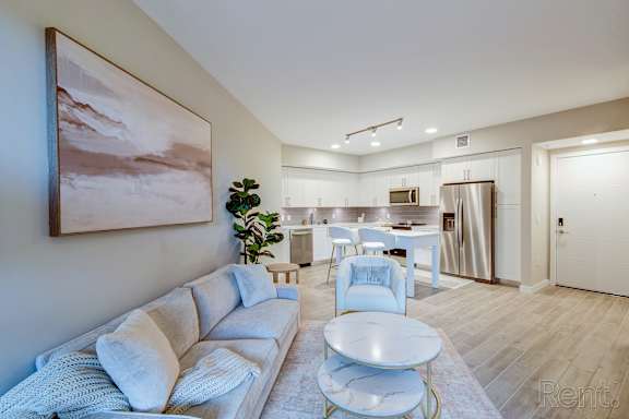 A living room with a white couch and a painting on the wall.