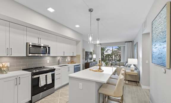 A modern kitchen with a large island and a view of the outdoors.