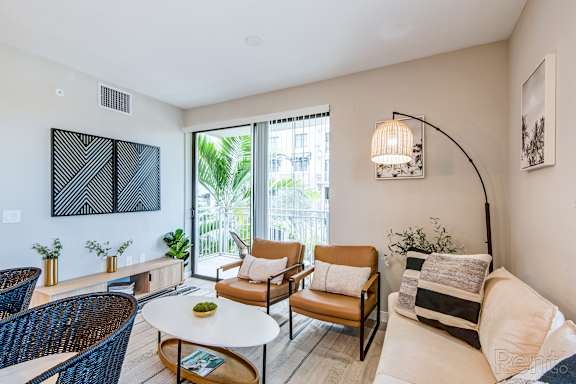 A living room with a white couch, a coffee table, and a large window.