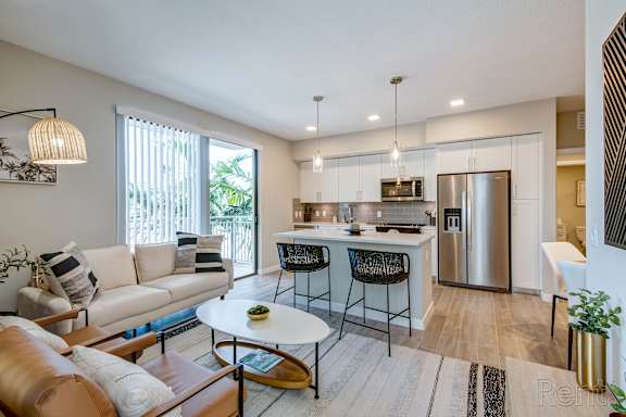 A modern kitchen with a breakfast bar and a dining table with chairs.