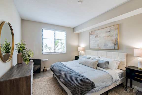 A bedroom with a large bed, a mirror, and a painting on the wall.