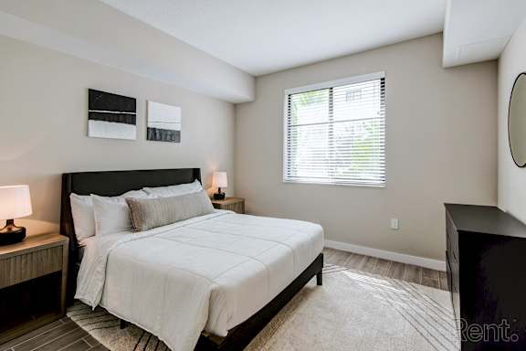 A bedroom with a large bed and a window with blinds.