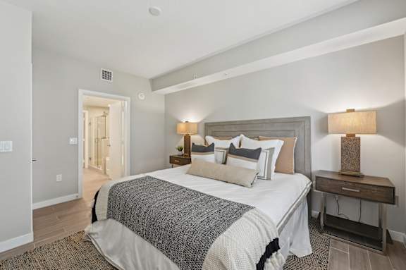 A bedroom with a large bed and a nightstand with a lamp.