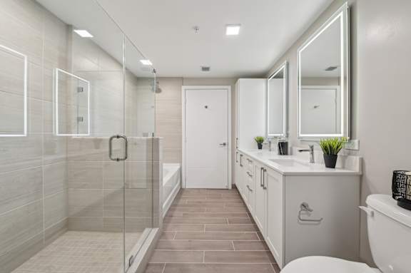 A modern bathroom with a walk-in shower and double sinks.