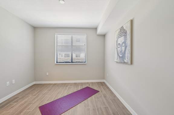 A yoga mat is on the floor of a room with a picture of Buddha on the wall.