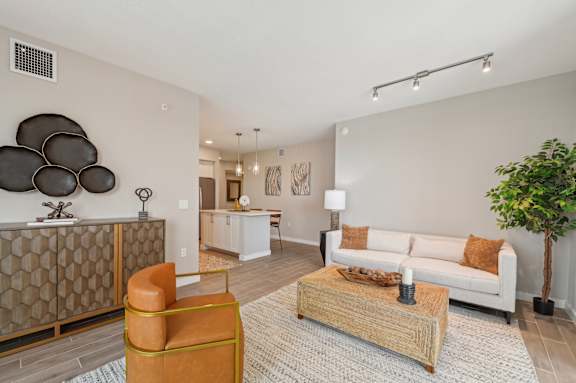 A living room with a white couch, a wooden coffee table, and a large abstract sculpture on the wall.