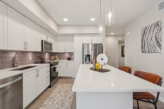 A modern kitchen with a white island and stainless steel appliances.
