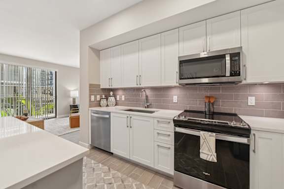 A modern kitchen with a stainless steel oven and white cabinets.