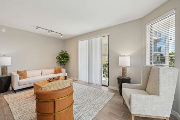 A living room with a white couch, a brown ottoman, and a grey rug.