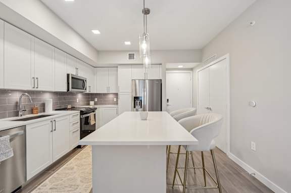 A modern kitchen with a white island and stainless steel appliances.