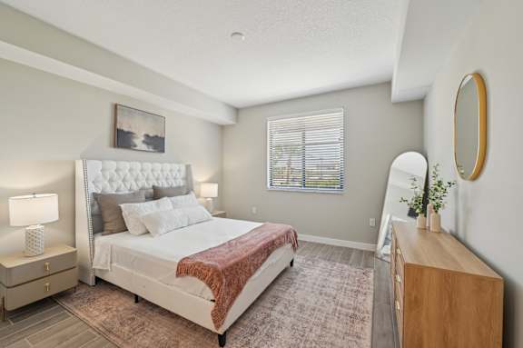 A bedroom with a large bed and a wooden dresser.