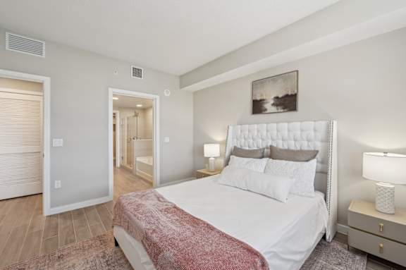 A bedroom with a large bed and a painting on the wall.