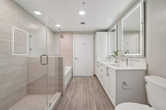 A modern bathroom with a walk-in shower and double sinks.