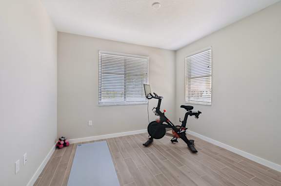 A room with a stationary bike and a yoga mat.