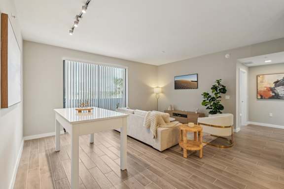 A living room with a white couch, a wooden coffee table, and a painting on the wall.