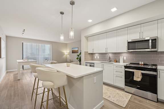 A modern kitchen with a white island and bar stools.