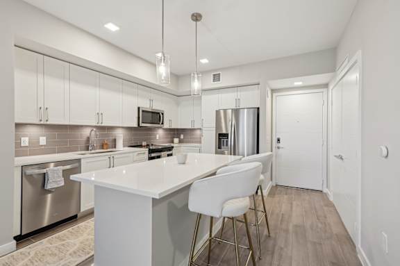 A modern kitchen with a white island and stainless steel appliances.