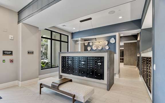 A modern waiting room with a bench and a large black board with many compartments at Mayla Pompano, Pompano Beach, FL