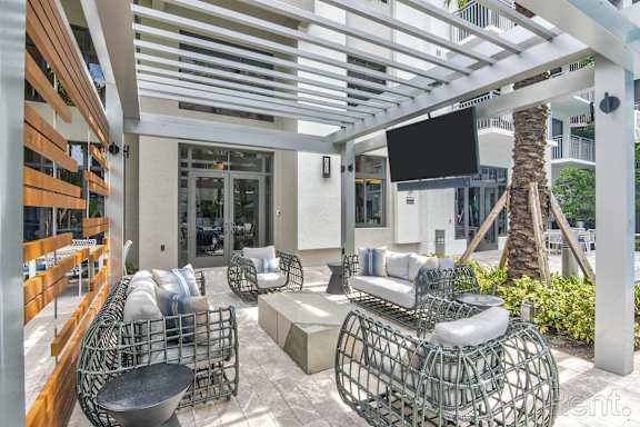 A patio with a white metal chair and a black TV mounted on the wall at Mayla Pompano, Pompano Beach, 33062