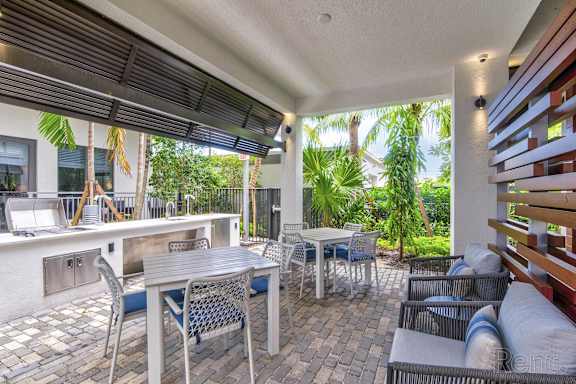 A patio with a table and chairs is covered by a roof at Mayla Pompano, Pompano Beach