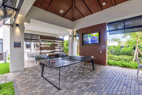 A patio with a table and chairs and a television on the wall at Mayla Pompano, Pompano Beach, FL