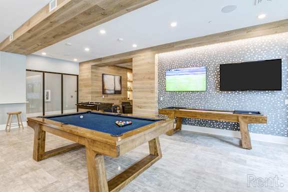 A pool table in a room with a TV and a bench at Mayla Pompano, Pompano Beach, 33062