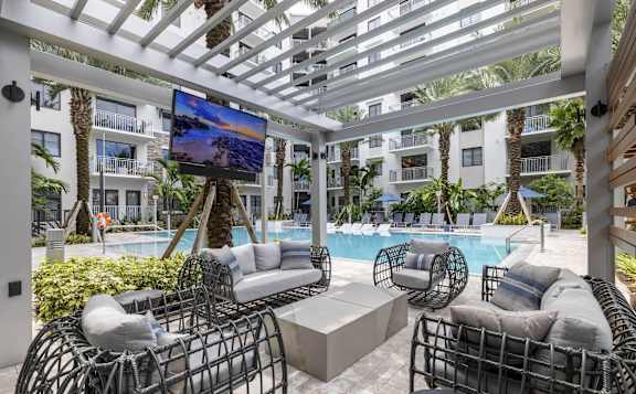 A patio with a television and a pool at Mayla Pompano, Pompano Beach