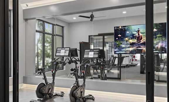 A modern gym with exercise bikes and a television at Mayla Pompano, Pompano Beach, FL