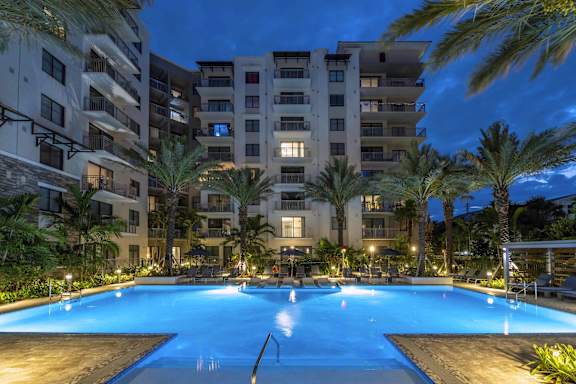 A swimming pool in front of a residential building surrounded by palm trees at Mayla Pompano, Pompano Beach, 33062