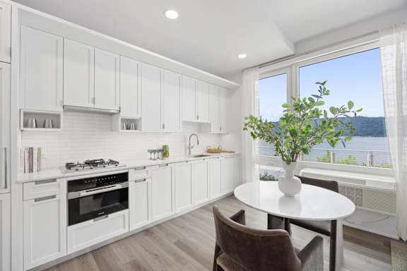 A kitchen with white cabinets and a table with a plant on it.