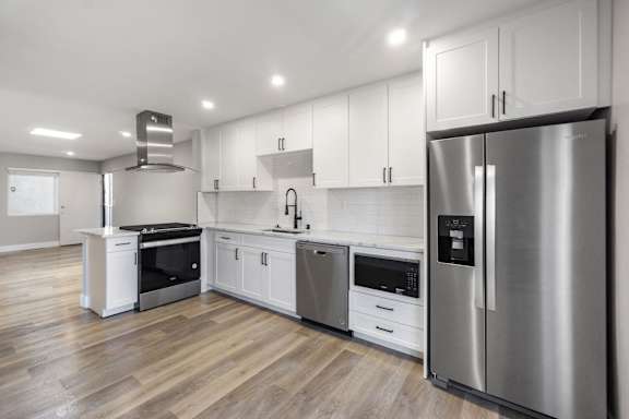 a white kitchen with stainless steel appliances and white cabinets at Ocean Breeze Terrace Apartment, Huntington Beach