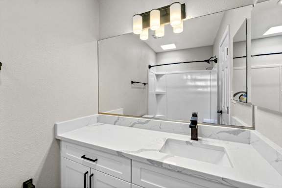 a bathroom with a sink and a mirror and a shower at Ocean Breeze Terrace Apartment, Huntington Beach, 92648