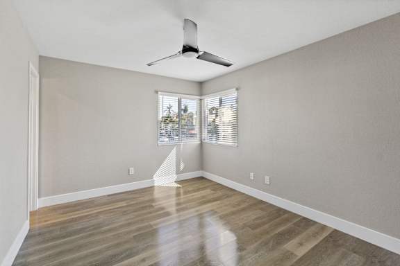 an empty living room with wood floors and a ceiling fan at Ocean Breeze Terrace Apartment, California